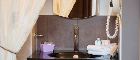 A bathroom with a black vanity, a sink, a towel rack, and a hairdryer.