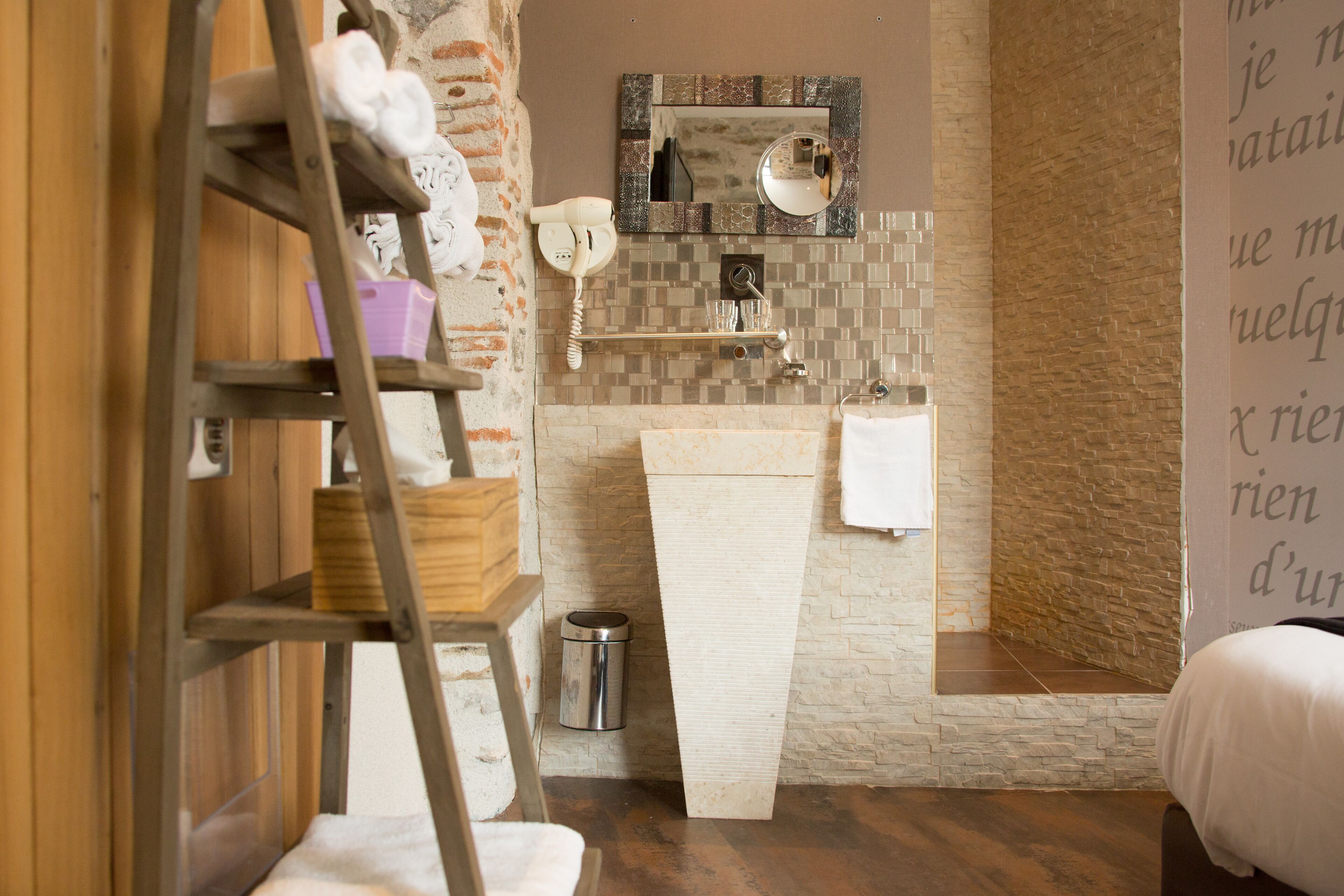 Une salle de bain avec une échelle en bois, un lavabo blanc, un miroir et une poubelle.