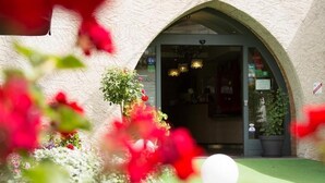 An arched entrance with a potted plant and a light fixture in the foreground. - Hôtel Le Turenne (Beaulieu-sur-Dordogne)