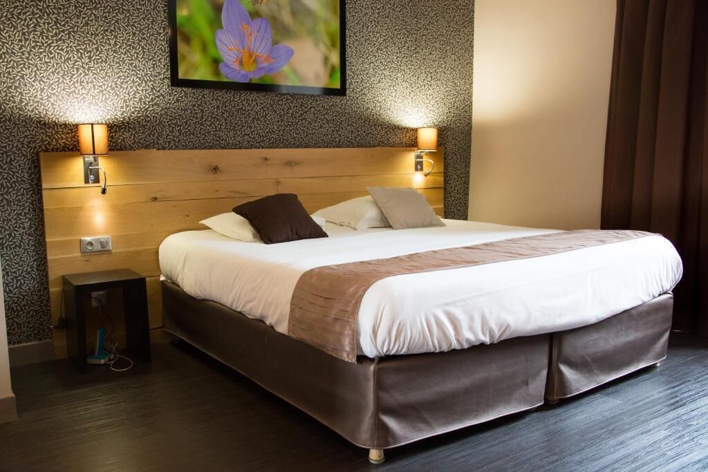 A neatly made bed with a wooden headboard, two bedside lamps, and a small nightstand with a lamp.