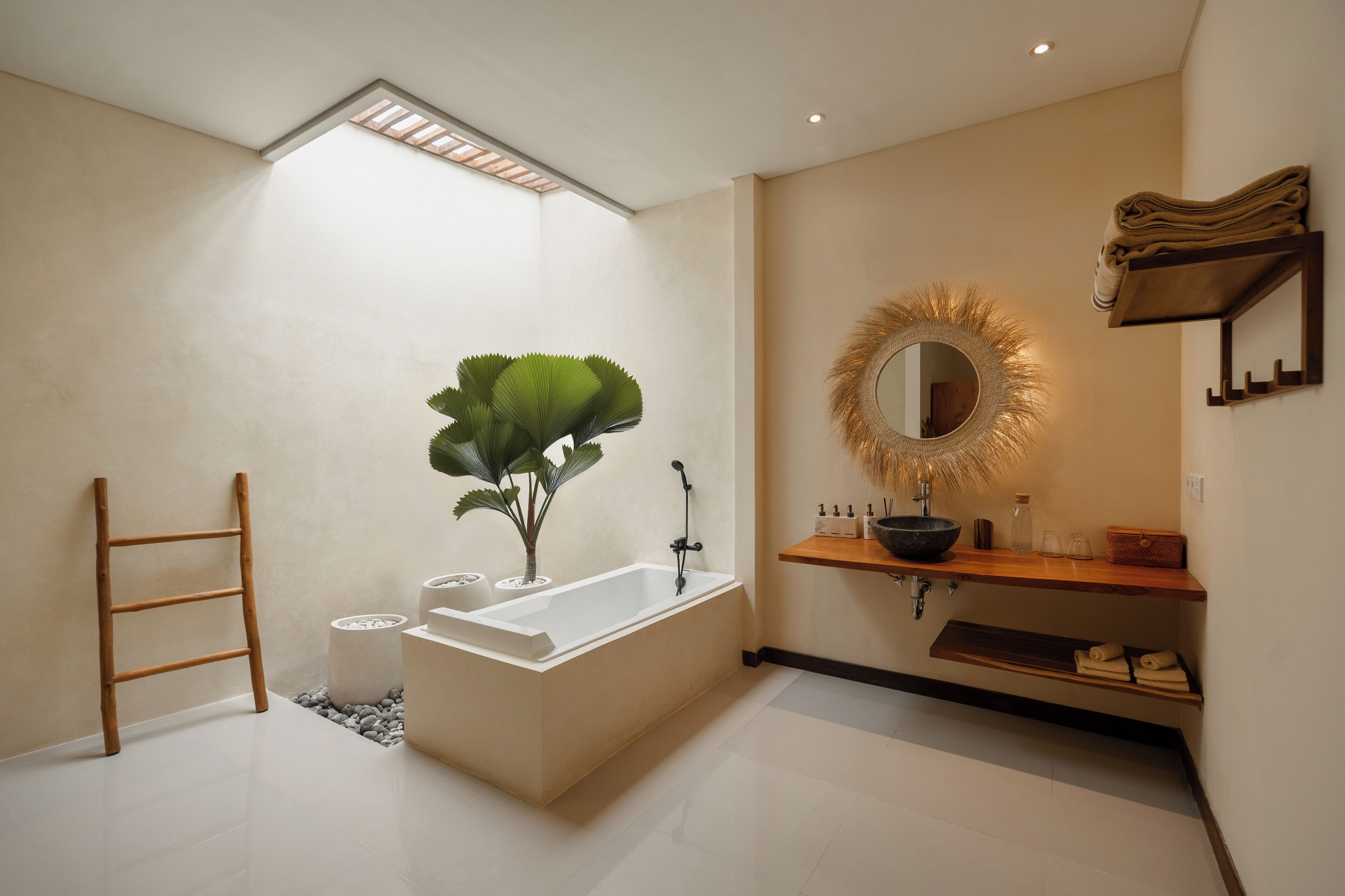 Un baño moderno con una bañera independiente, un espejo grande con un marco decorativo y un estante de madera con artículos de aseo.