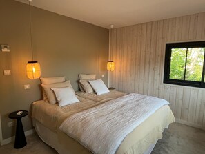 Relax in this serene bedroom with a large bed, wall-mounted lamps, and a window with a view.