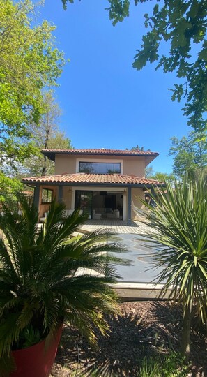Surrounded by lush greenery, this two-story house offers a tranquil retreat with a covered patio area.