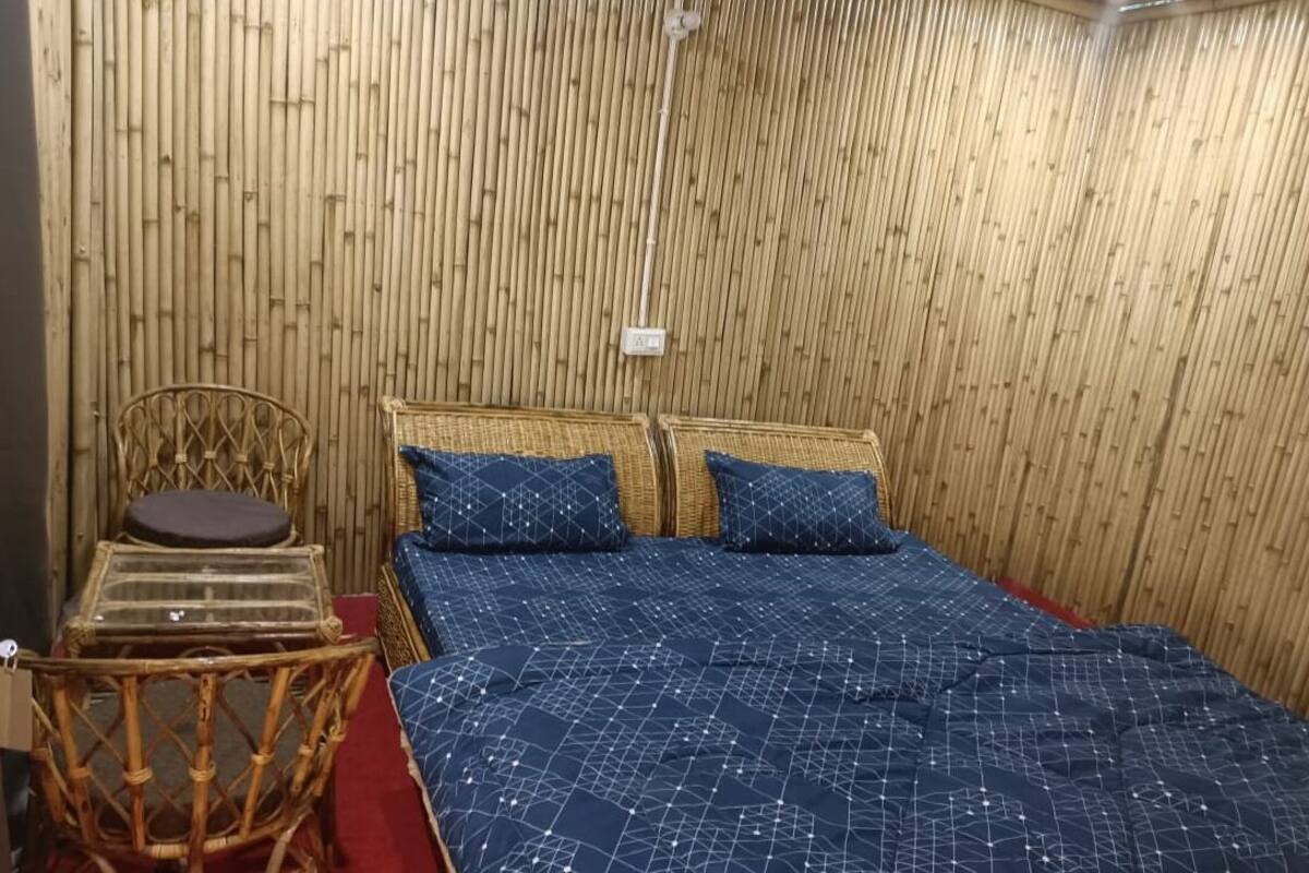 A room with a bed, two pillows, a chair, and a small table.