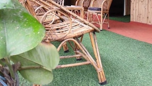 Una habitación con techo de bambú, suelo de césped artificial y mobiliario de mimbre.