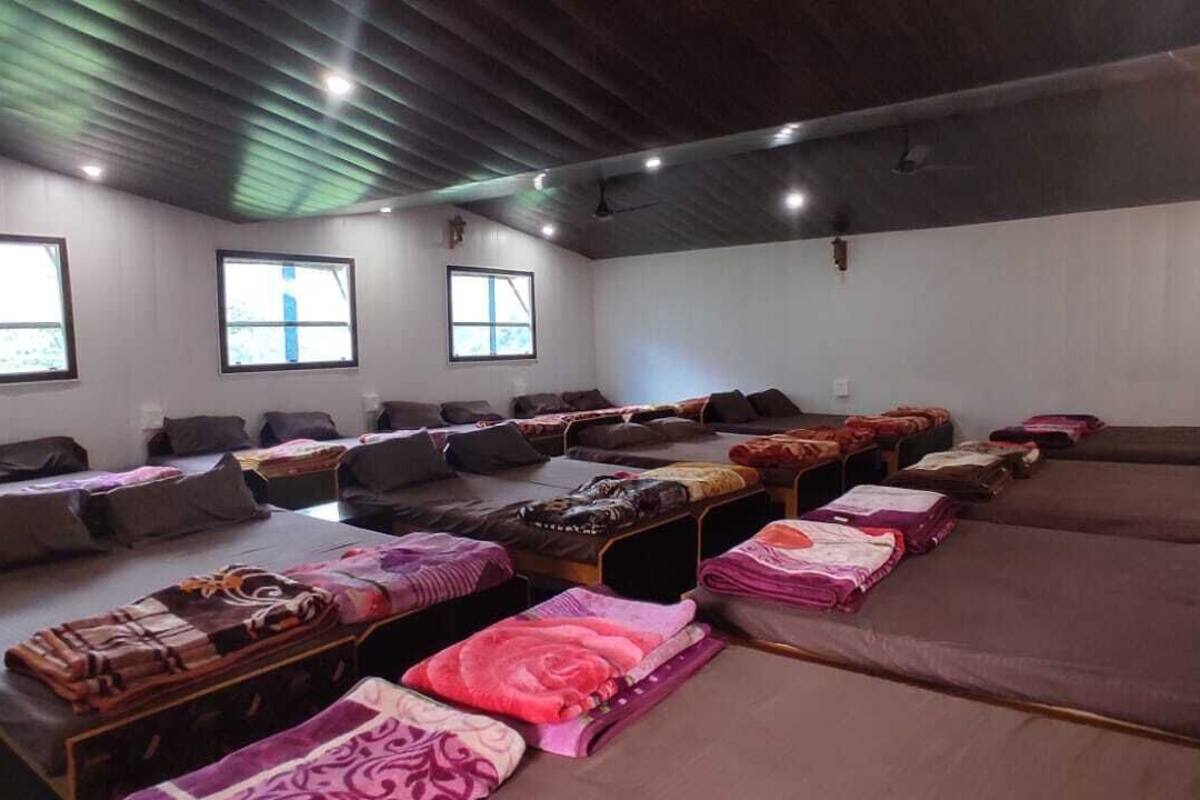 A room with multiple beds arranged in rows, each with a pillow and blanket.