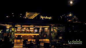 A nighttime view of a bar area with a neon sign reading "Sky Lounge," outdoor seating, and a staircase leading to an upper level. - La Grande Residence- Grand Studio - Angeles/ Clark (Angeles)