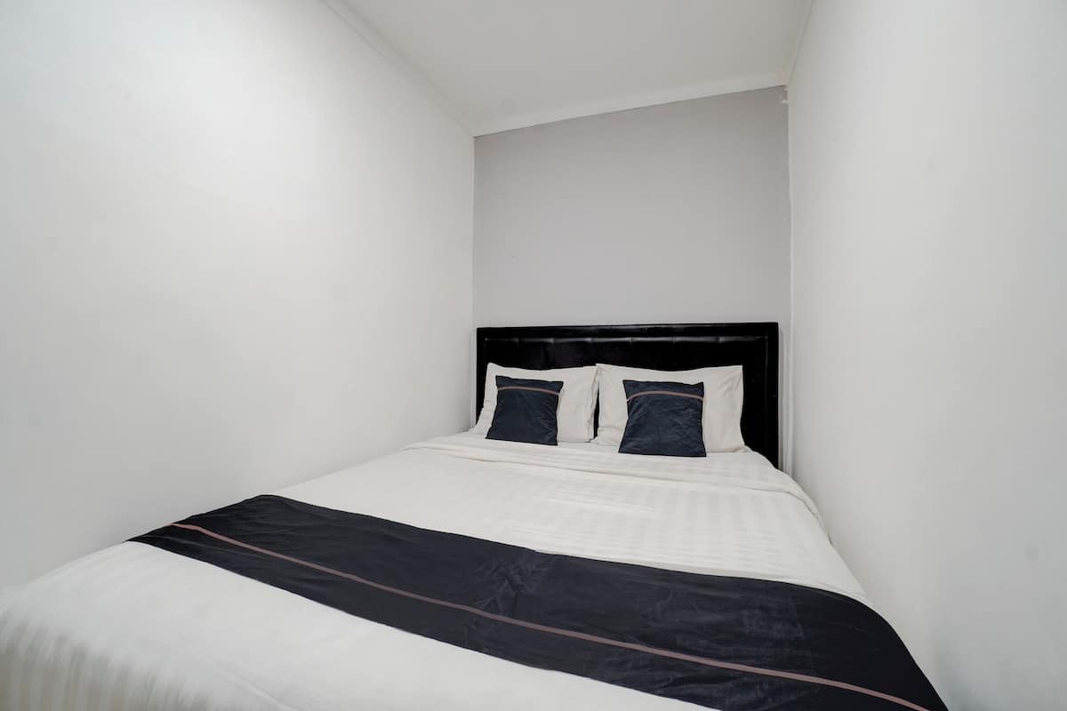 Una cama bien hecha con una colcha blanco y negro y dos almohadas.