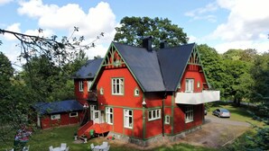 A red house with a balcony, surrounded by a grassy yard and white chairs. - AlingsÃ¥s Vandrarhem - Villa Plantaget - Hostel (Alingsas)