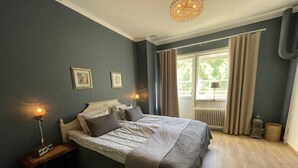 A bedroom with a bed, bedside tables, a window with curtains, and a radiator. - AlingsÃ¥s Vandrarhem - Villa Plantaget - Hostel (Alingsas)