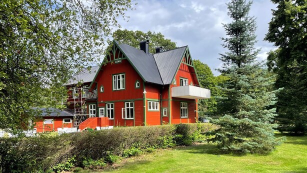 A red two-story house with a balcony, surrounded by greenery and trees. - AlingsÃ¥s Vandrarhem - Villa Plantaget - Hostel (Alingsas)