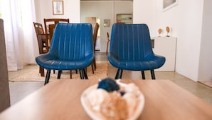 Ein Essbereich mit zwei blauen Stühlen, einem Holztisch und einer Schüssel mit Essen.