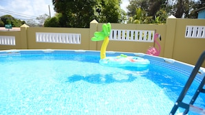 Ein Swimmingpool mit einer Leiter, einem gelb-grünen aufblasbaren Poolspielzeug und einem rosa Flamingo-Schwimmtier.