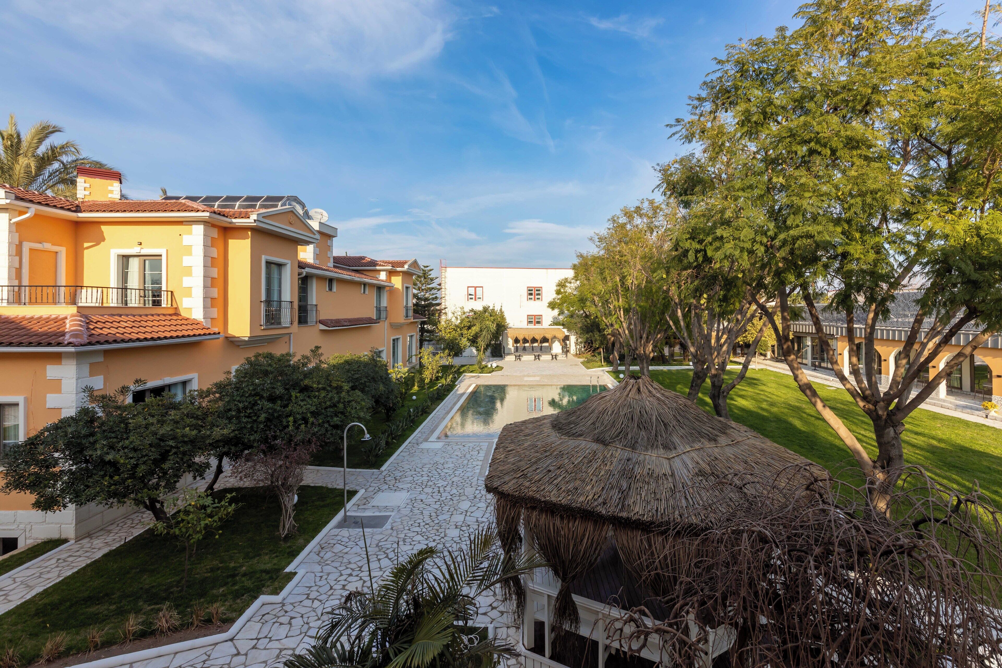 A resort with a swimming pool, thatched-roof structures, and a well-maintained lawn.