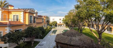 A resort with a swimming pool, thatched-roof structures, and a well-maintained lawn.