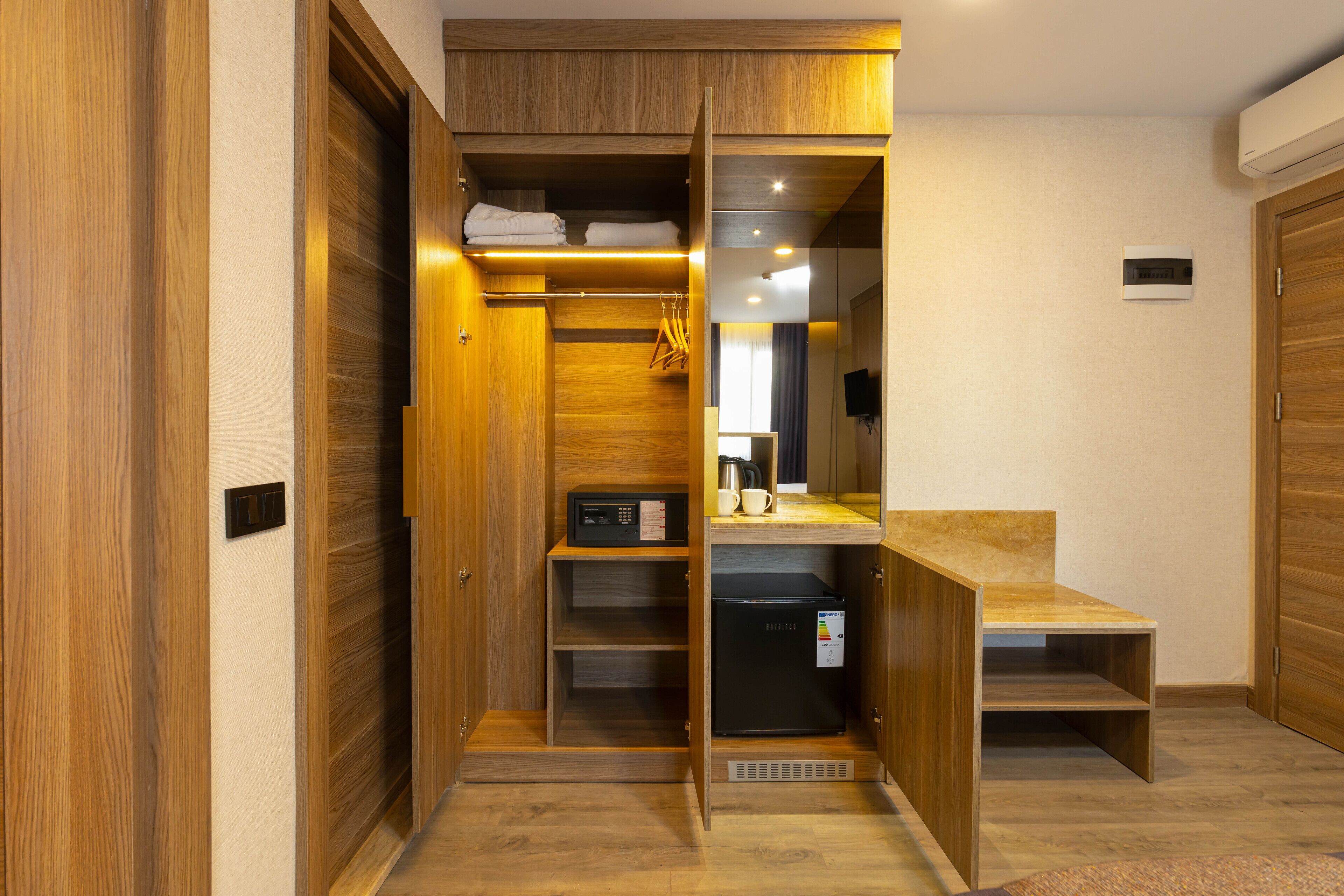 A compact, modern room with built-in wooden cabinets, a built-in microwave, and a small refrigerator.
