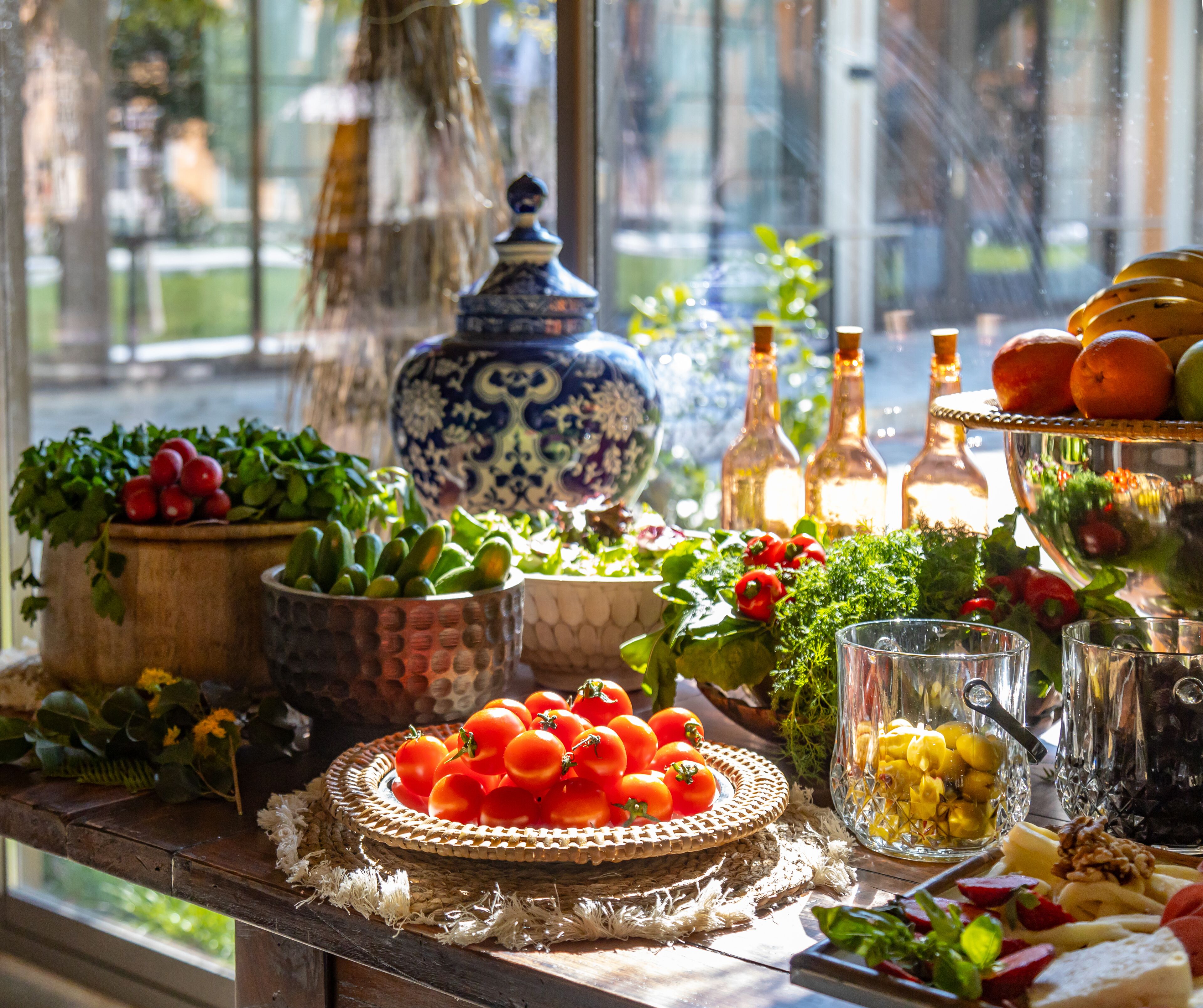 Uma mesa com várias frutas, legumes e copos, indicando uma disposição para refeições ou lanches.