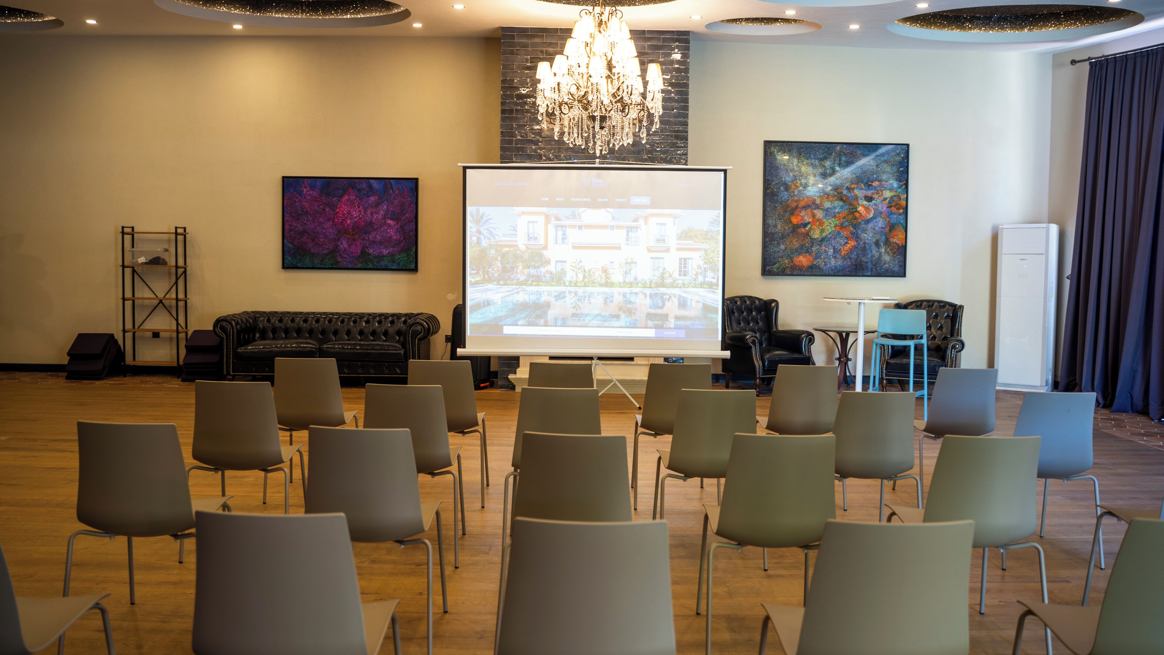 A conference room with a projector screen, a black sofa, and modern chairs arranged for a meeting.