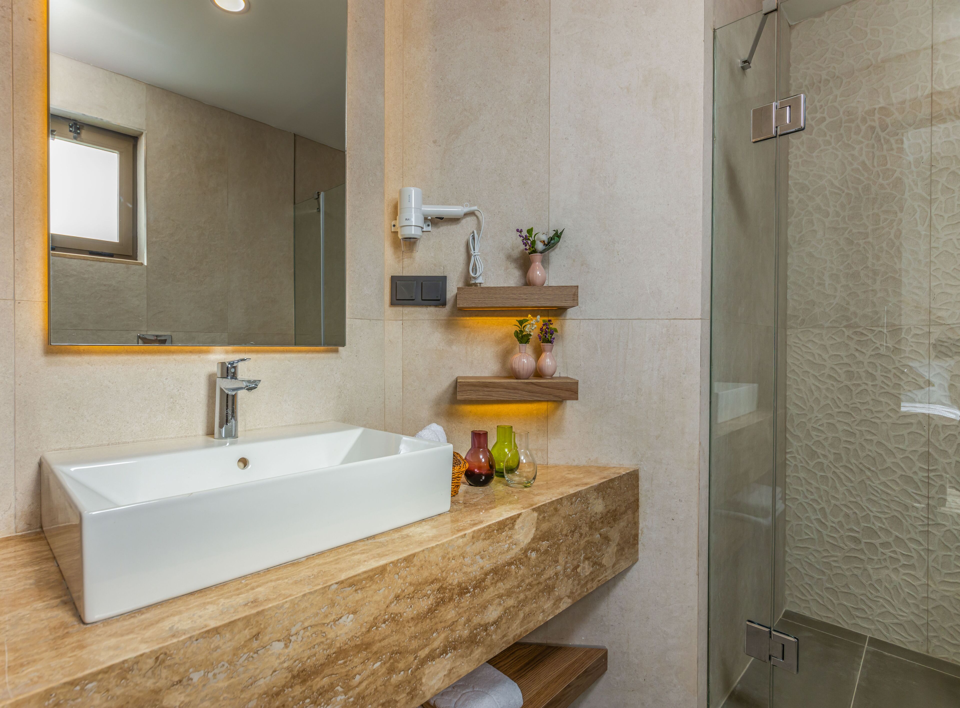 Un baño con un lavamanos rectangular grande, un espejo, un perchero para toallas y una zona de ducha.