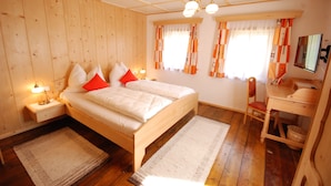 Ein Zimmer mit Holzwandverkleidung, das ein Bett, Nachttische, einen Schreibtisch und einen Sessel beherbergt.
