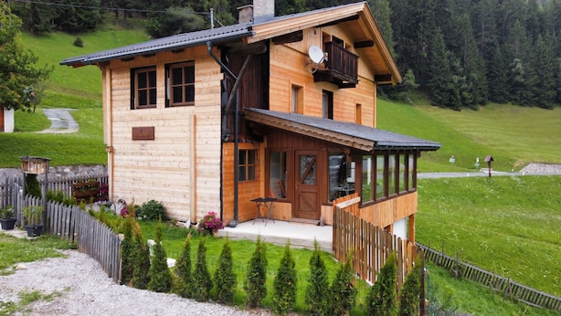 Eine Holzhütte mit Balkon, einer Tür und einer kleinen Veranda.