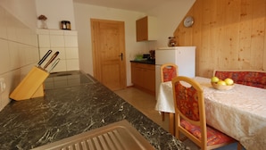 Eine Küche mit Marmorarbeitsplatte, Holzschränken und einem Essbereich mit Tisch und Stühlen.