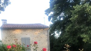 A stone building with a tiled roof and a wooden shutter.