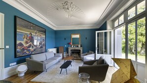 A living room with a fireplace, sofas, a coffee table, and a large abstract painting.