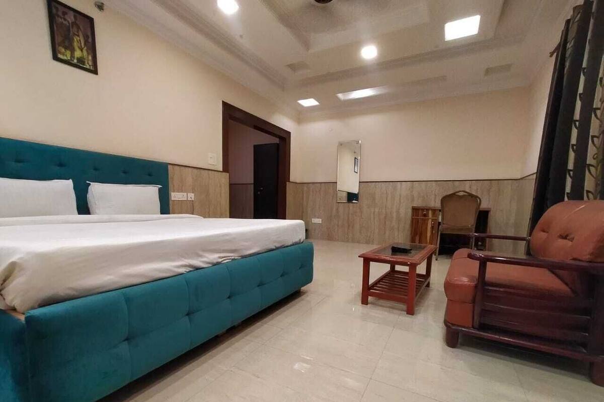 Ein Schlafzimmer mit einem großen Bett, einem Holzstuhl, einem kleinen Tisch und einem Spiegel an der Wand.