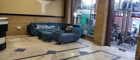 A waiting area with a blue sofa set and a reception desk.