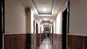 A long, narrow hallway with a marble floor and wooden paneling on the walls. - Redisston Hotel By GRB (Noida)