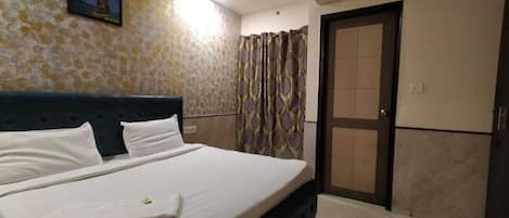 A hotel room with a bed, a television on the wall, an air conditioning unit, and a door with a view of the outside.