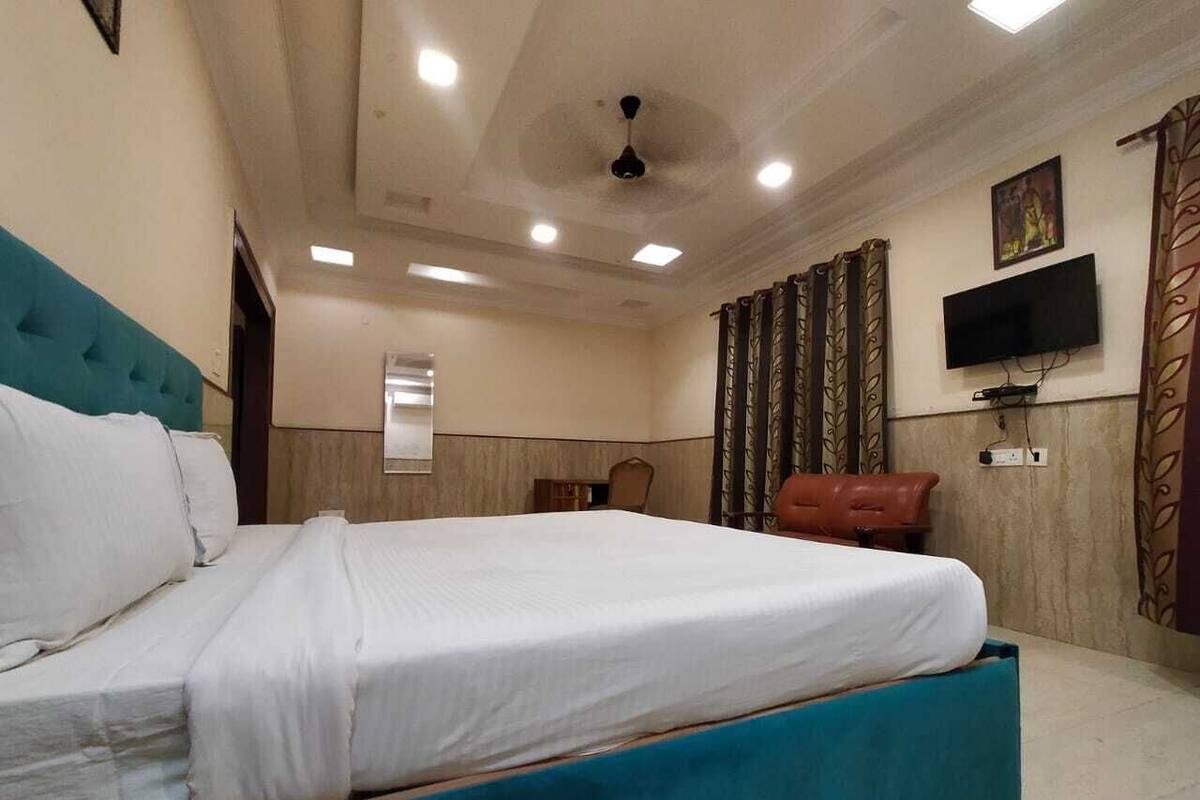 Ein Hotelzimmer mit einem großen Bett, einem an der Wand montierten Fernseher und einem Deckenventilator.