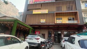 A hotel with multiple floors, including a visible SS Banquet on the second floor. There are several parked cars and motorcycles in front of the hotel. - Redisston Hotel By GRB (Noida)