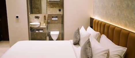 Una habitación de hotel moderna con una cama grande, baño integrado y pared de mármol.