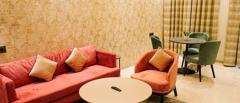 A living room with a red sofa, two armchairs, a small round table, and a green chair.