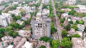 Vista aérea de un paisaje urbano con un edificio moderno destacado, rodeado de zonas residenciales y vegetación.