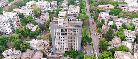 An aerial view of a cityscape with a prominent modern building surrounded by residential areas and greenery.