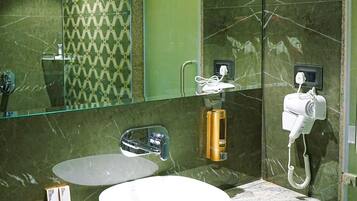 Un baño moderno con un espejo grande, un lavabo blanco y un secador de pelo montado en la pared.