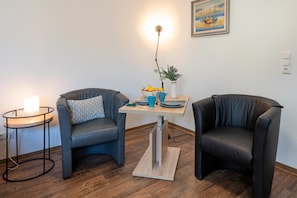 A room with two leather chairs, a small table with a vase of flowers, and a painting on the wall. - Traumhafte Strandnah-wohnung in Koserow für Zwei (Koserow)