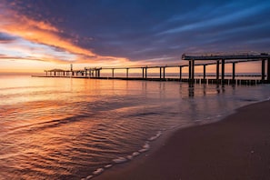 Une jetée s’avançant dans des eaux calmes, avec un ciel au coucher du soleil.