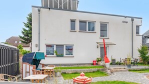 Een gebouw met twee verdiepingen, een plat dak, een zichtbare schoorsteen en een naambordje aan de zijkant.