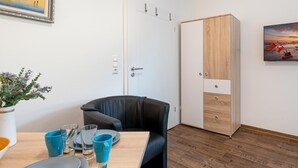 Een kamer met een eettafel gedekt voor twee personen, een zwarte leren stoel, een witte kledingkast en een schilderij aan de muur.