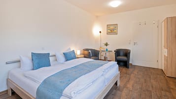 A neatly arranged bedroom with a bed, bedside table, lamp, and a chair.