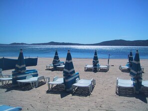 A beach with rows of sun loungers and umbrellas, a clear sky, and a calm sea. - Port Grimaud 1 Beau Studio 40 m2 Avec Terrasse sur Plage - Magnifique vue (Grimaud)