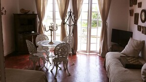 Una stanza con un tavolo da pranzo, sedie, un lampadario, una televisione e un letto.