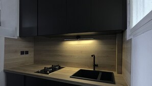 Una cucina moderna con mobili scuri, un piano di lavoro in legno e un piano cottura a gas integrato.
