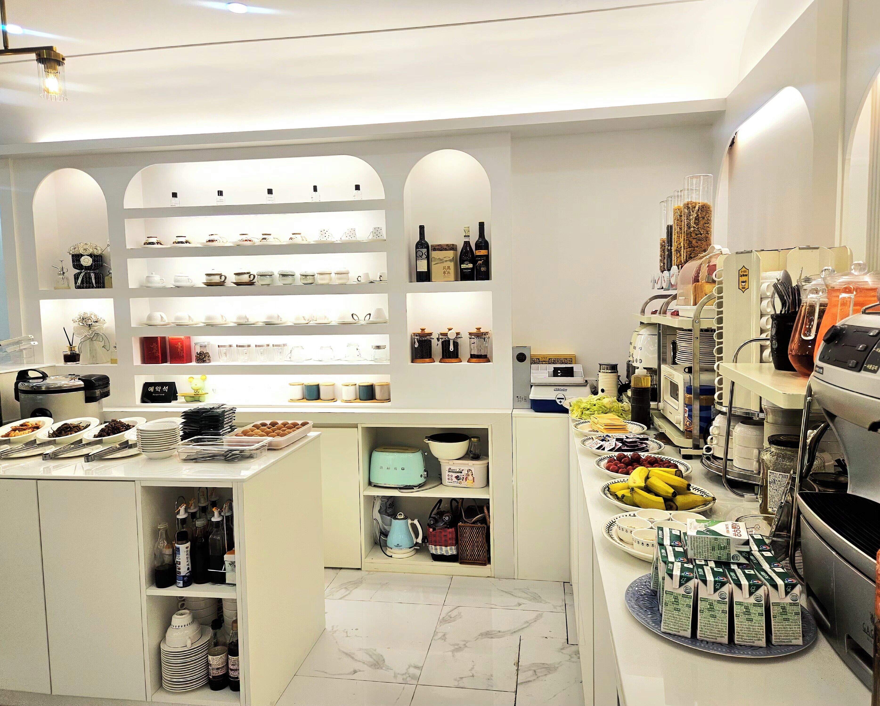 A well-organized kitchen with various appliances, shelves with kitchenware, and a coffee station.