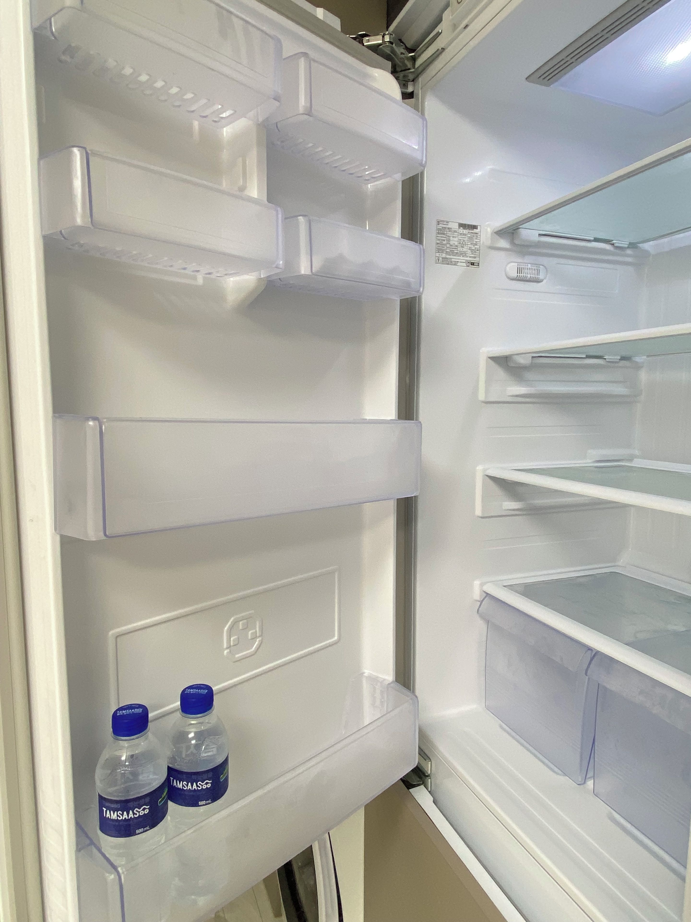 Ein offener Kühlschrank mit mehreren Regalen und zwei Wasserflaschen auf der untersten Ablage.