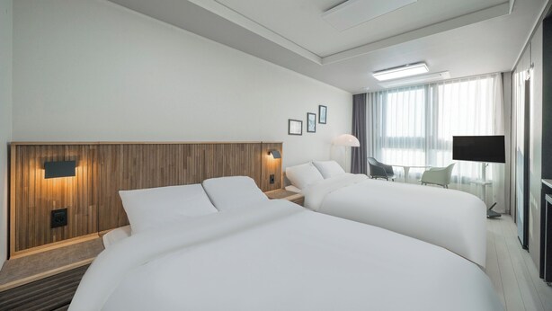 A hotel room with two beds, a wooden headboard, a flat-screen TV, and a balcony with a view. - Daegu Dongseongro Star B&B Business Hotel (Daegu)